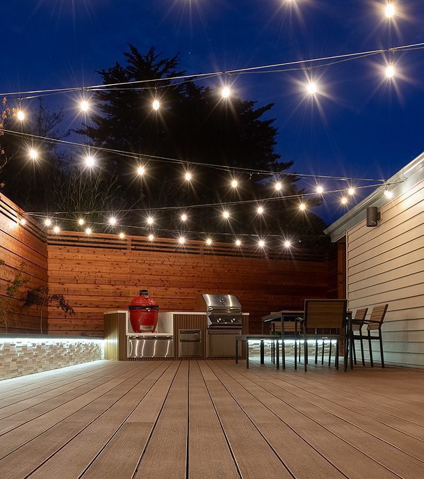 Backyard deck at night with string lights and seating