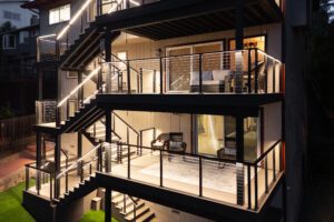 Three-story deck with glass railing lit at night