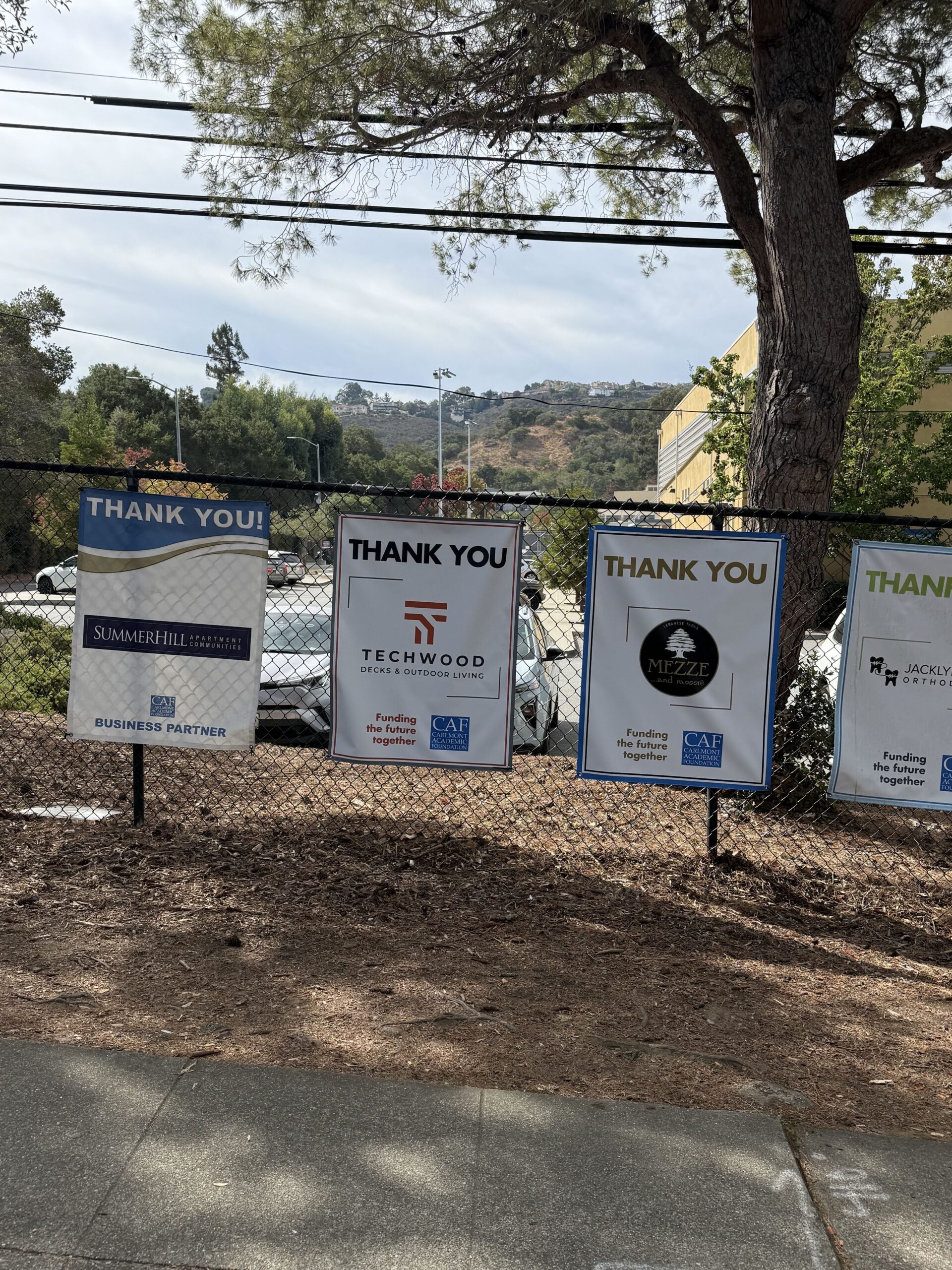 Carlmont Academic Foundation business partner banners on the fence at Carlmont High School, including Techwood Decks
