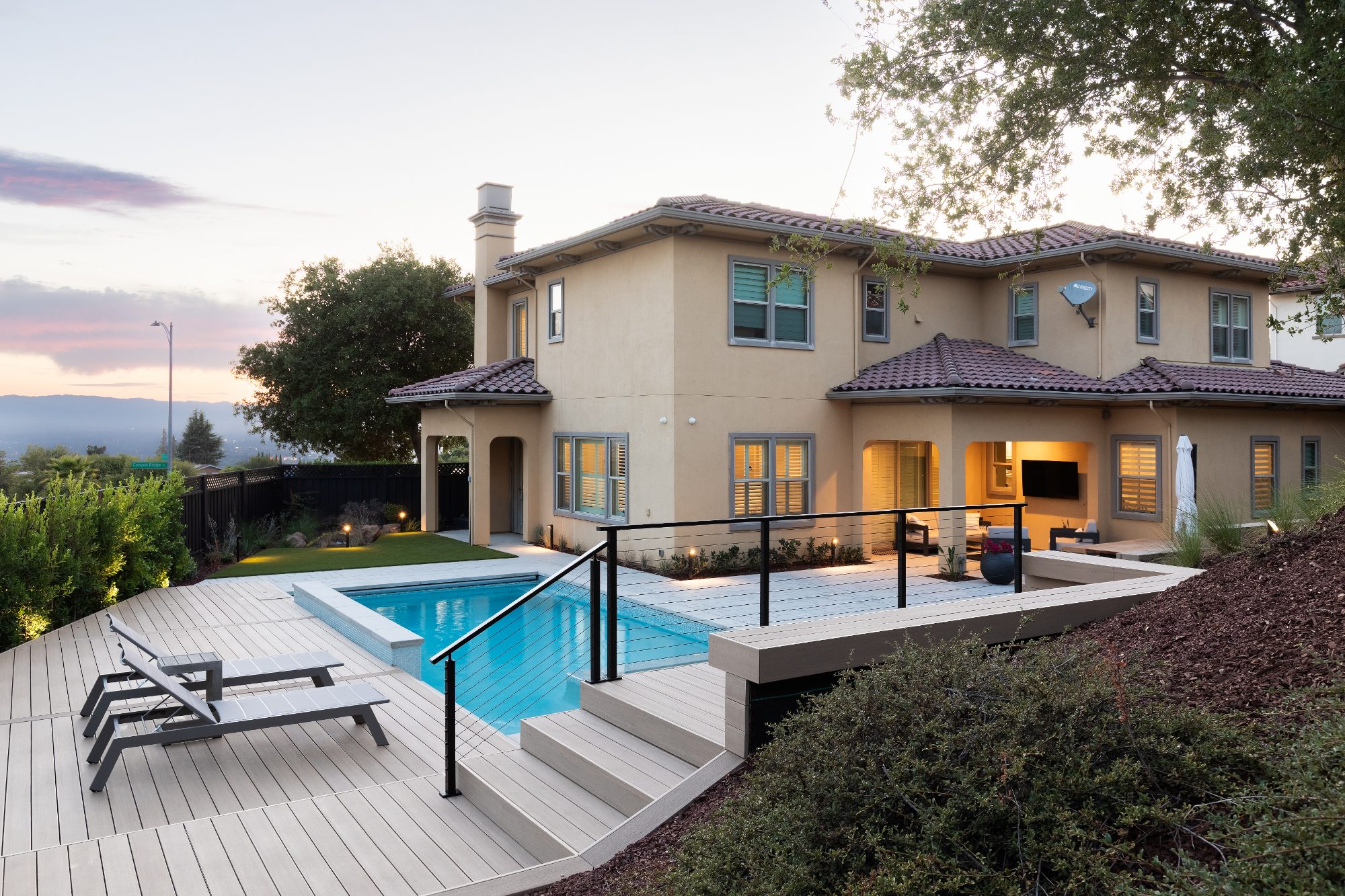 Deck stairs with black railing beside a pool in San Jose, CA